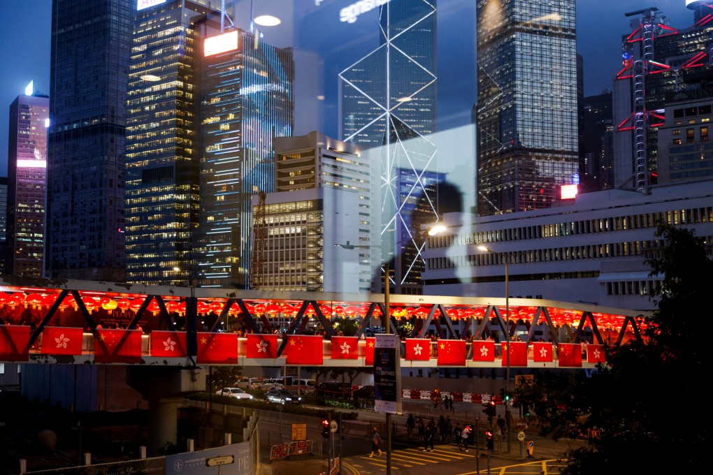 The reflection of a man is seen on a windowpane, while a pedestrian footbridge in the background is adorned with China’s and Hong Kong’s flags as decorations for the celebration of National Day, in Hong Kong, on October 3, 2023. Photo: Tyrone Siu