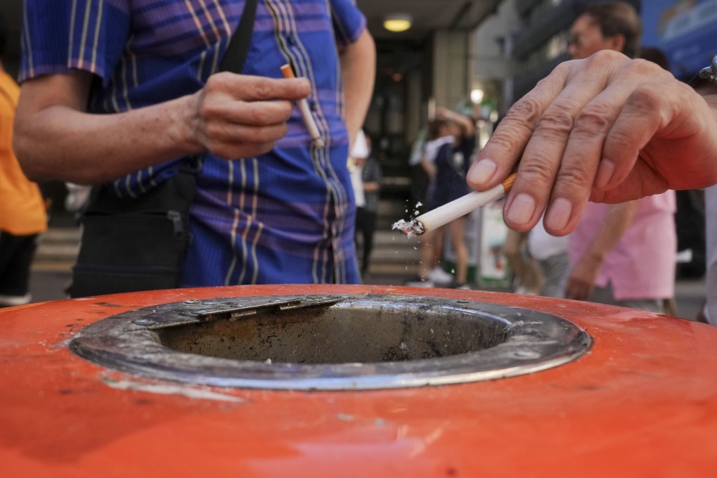 Smokers place their cigarette butts inside a rubbish bin in Wan Chai in July 2023. Photo: Elson Li