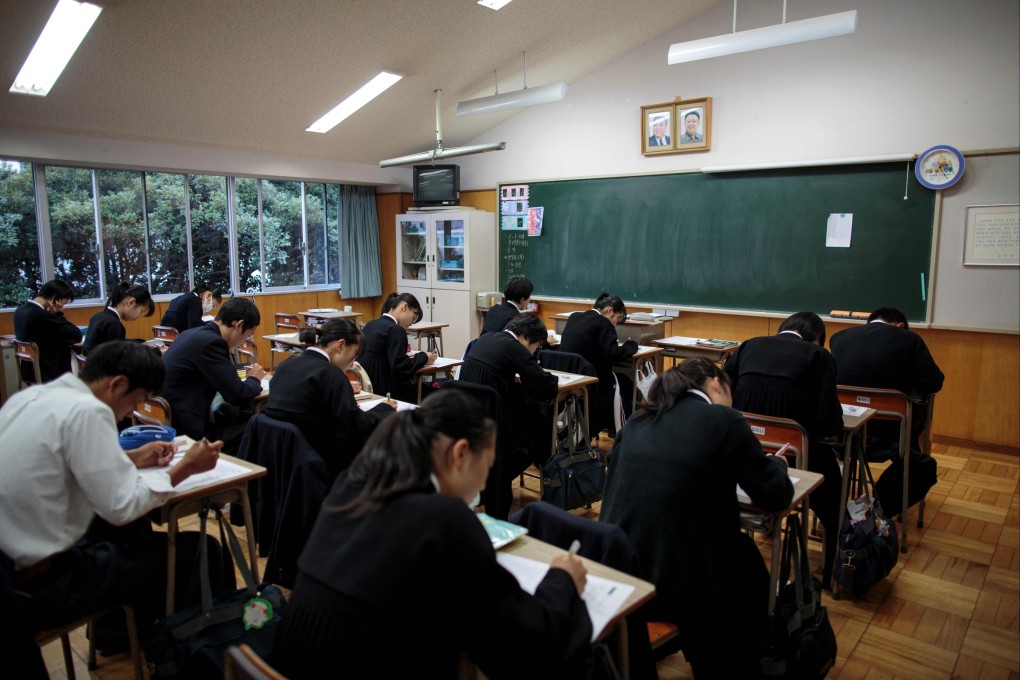 Students take an exam as portraits of late North Korean leaders Kim Il-sung and Kim Jong-il are seen in a classroom at a Korean school in Tokyo, Japan. Photo: AFP