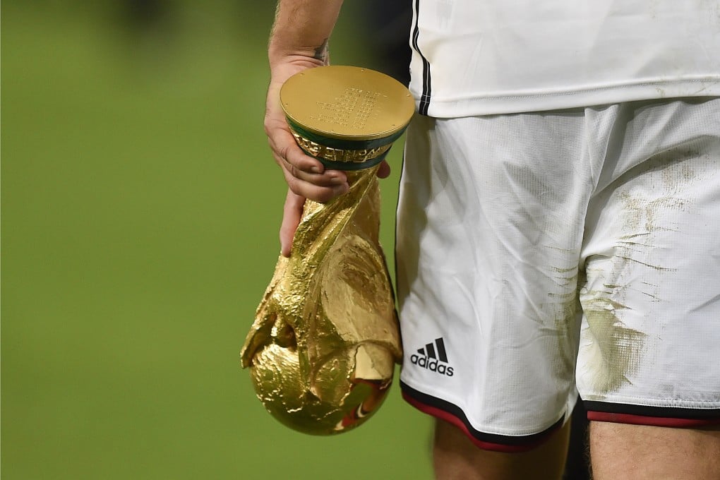Germany’s Lukas Podolski holds the World Cup trophy and wearing Adidas at the 2014 tournament. Photo: AP