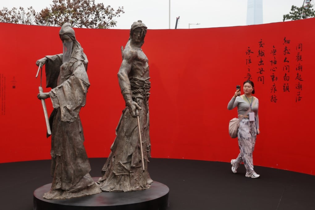 A visitor takes a photo of the sculptures of Xiaolongnu and Yang Guo, the central couple of the Jin Yong novel, “The Return of the Condor Heroes”, at Edinburgh Place in Central on March 15. Photo: Yik Yeung-man