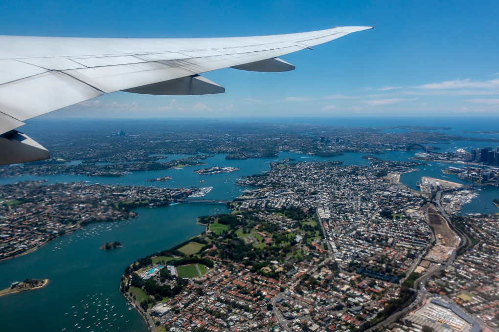 Sydney Harbour seen from a flight newly taken off from Sydney for Los Angeles. Rising airfares, the carbon cost of long-haul travel and the prospect of fewer flights and even higher fares are headwinds for the travel industry in Australia and New Zealand. Photo: Shutterstock