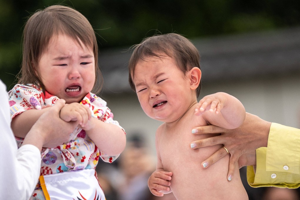 Young children are held aloft by their parents at a “baby-crying” competition in Tokyo last year. There were just 758,631 children born in Japan in 2023, a record low. Photo: AFP