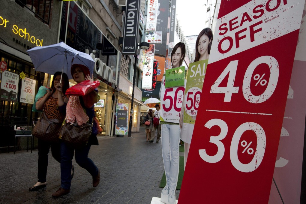 South Korean people pass a store advertising discount sales in Seoul, South Korea. Photo: EPA/File