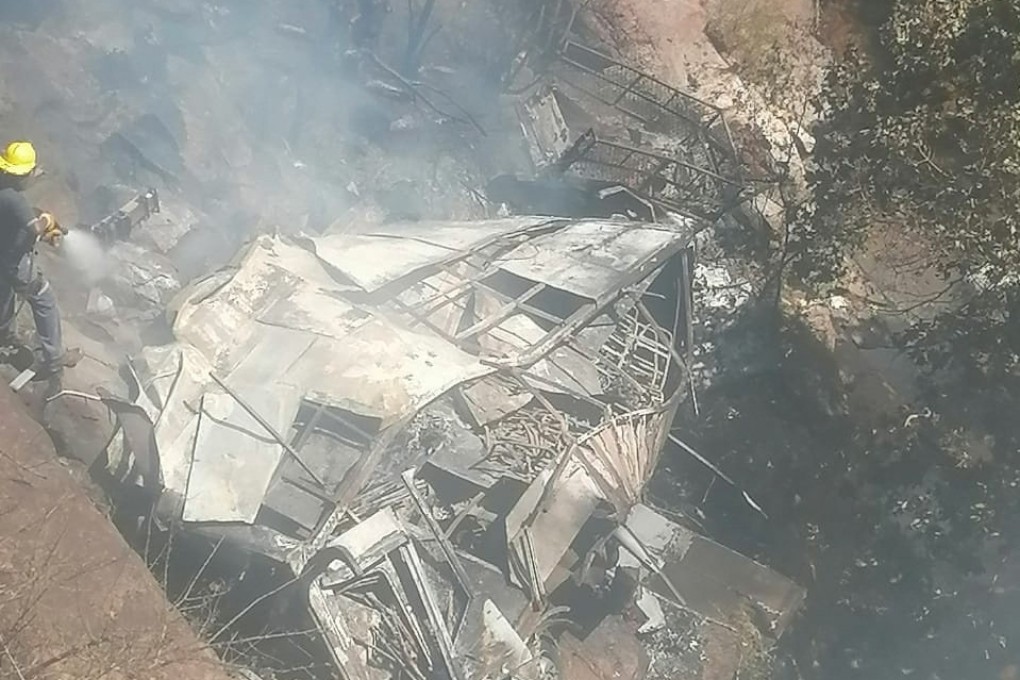 Firefighters hose down the wreckage of a bus after it crashed in Limpopo Province, South Africa on Thursday. Photo:   Limpopo Department of Transport and Community Safety via Reuters