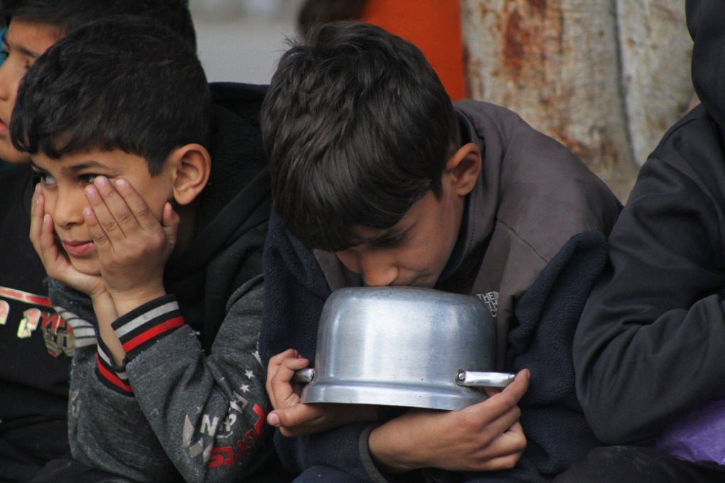 Palestinian children wait to collect food handouts from a street kitchen in Deir al-Balah, central Gaza on Sunday. Photo: Bloomberg