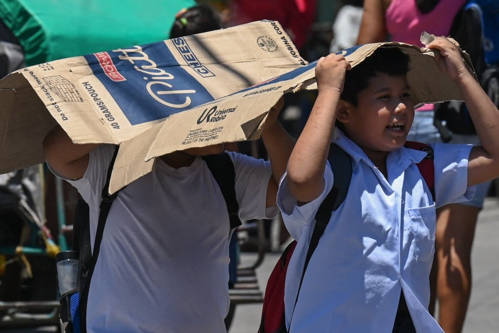Students use a cardboard to protect themselves from the sun during a hot day in Manila on Tuesday. More than a hundred schools in the Philippine capital shut their classrooms as the tropical heat hit “danger” levels. Photo: AFP