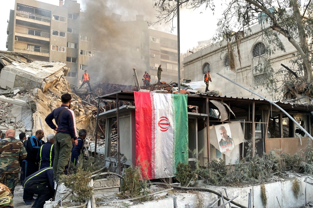An Iranian flag hangs as smoke rises after what Iranian media said was an Israeli strike on a building close to the Iranian embassy in Damascus, Syria on Monday. Photo: Reuters