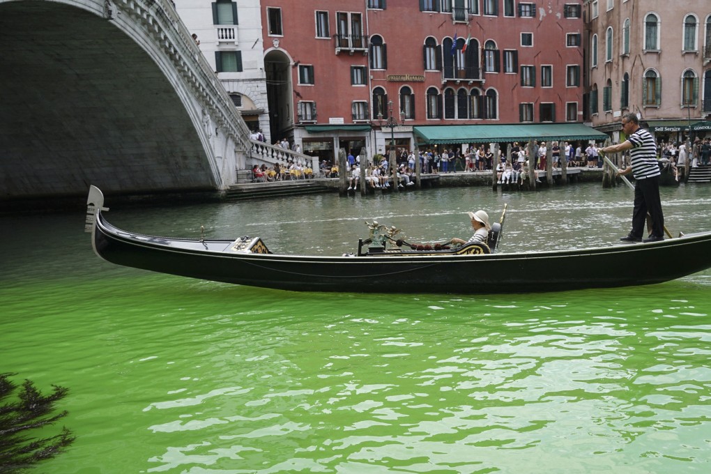 A gondolier propels a gondola along a patch of phosphorescent green liquid seen on the Grand Canal near the Rialto Bridge in Venice. Dozens of raids were conducted with arrests in Italy, Austria, Romania and Slovakia as a result of an investigation into an alleged criminal network. Photo: EPA-EFE
