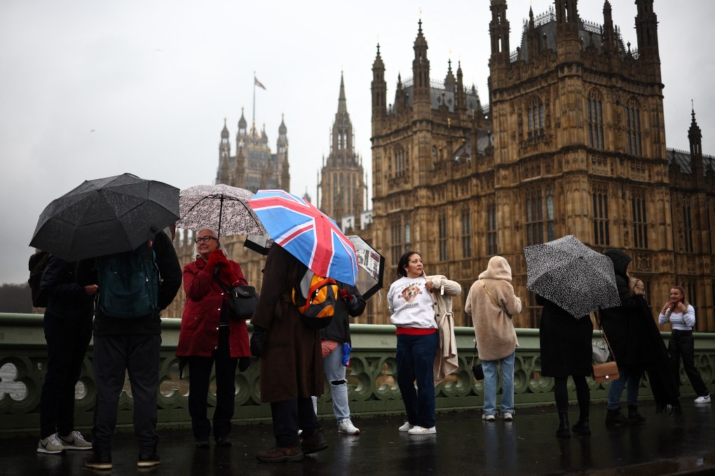 Tourists shelter from the rain as they walk over Westminster Bridge, in London, the UK, on March 10, 2024. This winter the UK has endured relentless rain, while in Hong Kong, unseasonably warm weather saw March temperatures hit their highest ever. Photo: AFP
