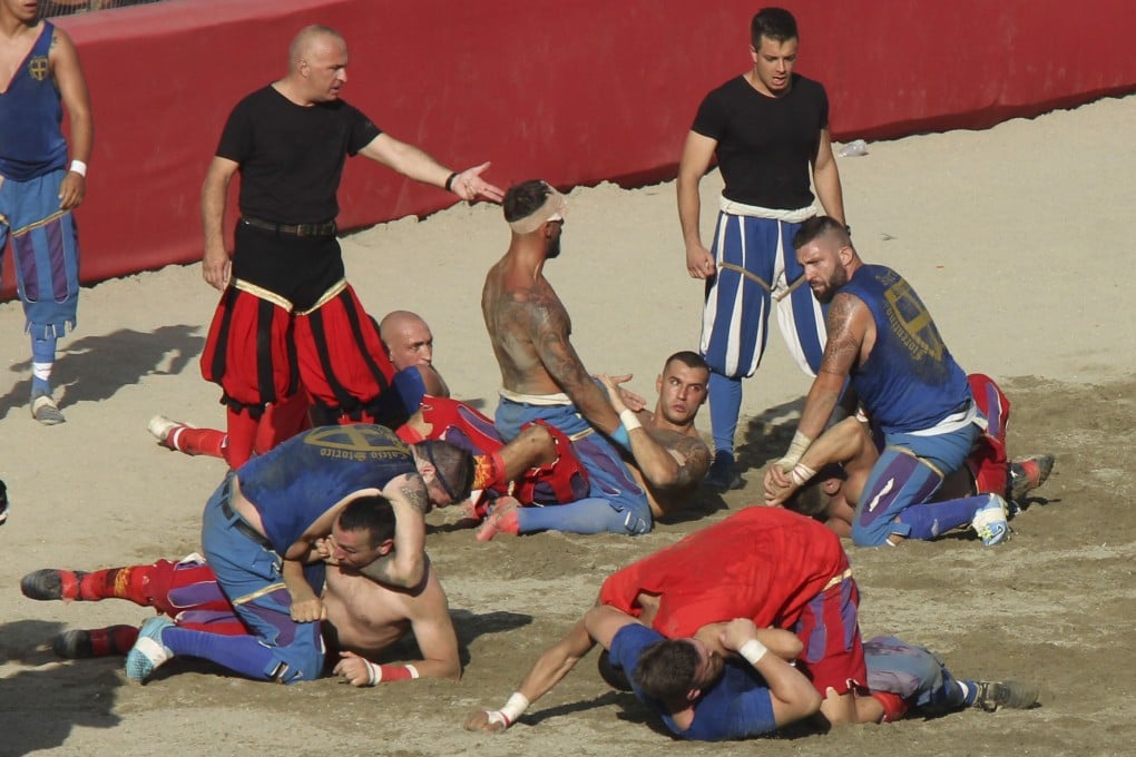 The Rossi of Santa Maria Novella (in red) take on Santa Croce’s Azzuri (in blue) watched by referees (in black) in the 2023 Calcio Storico Fiorentino, in Florence, Italy, Combining the sports of football, rugby, wrestling and street fighting, the event is one of the world’s most violent sports. Photo: John Brunton