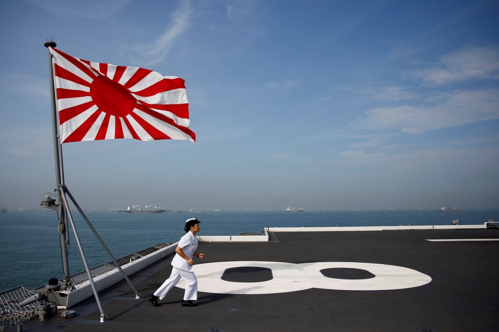 A navigator runs back to her post after raising the Rising Sun Flag, the Japanese naval ensign, aboard the Kaga in 2018 while it was still a helicopter carrier. Photo: Reuters