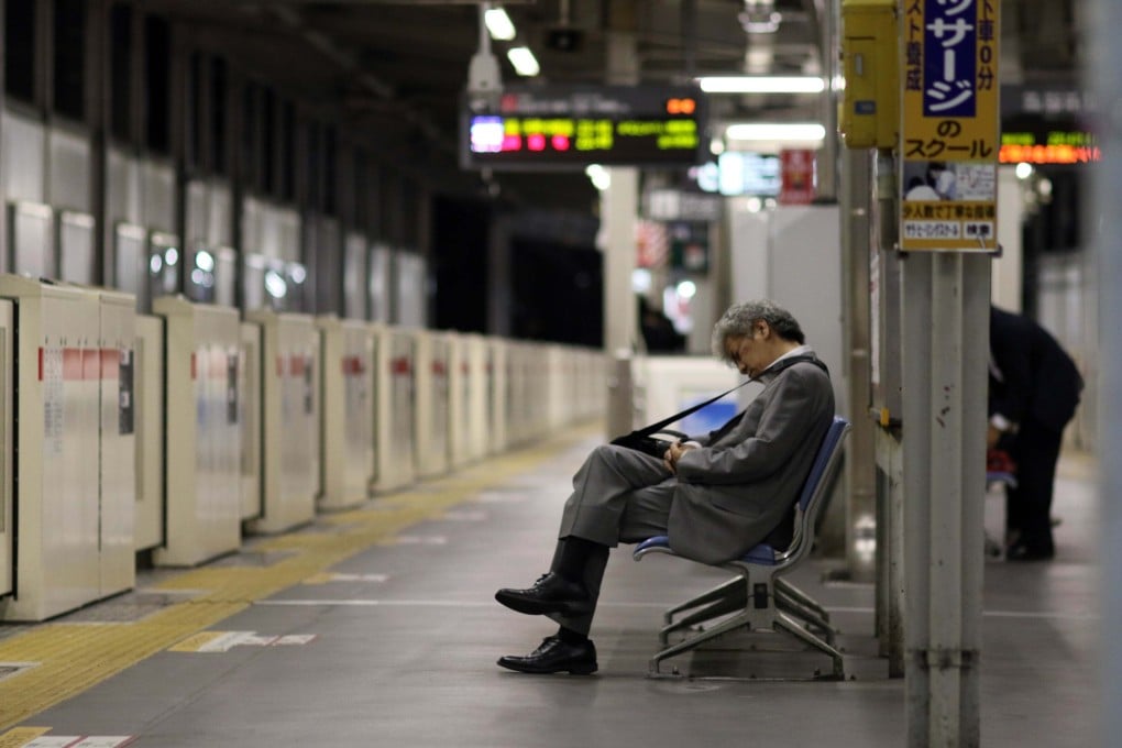 A businessman sleeping on a bench at a Tokyo train station. Photo: AFP