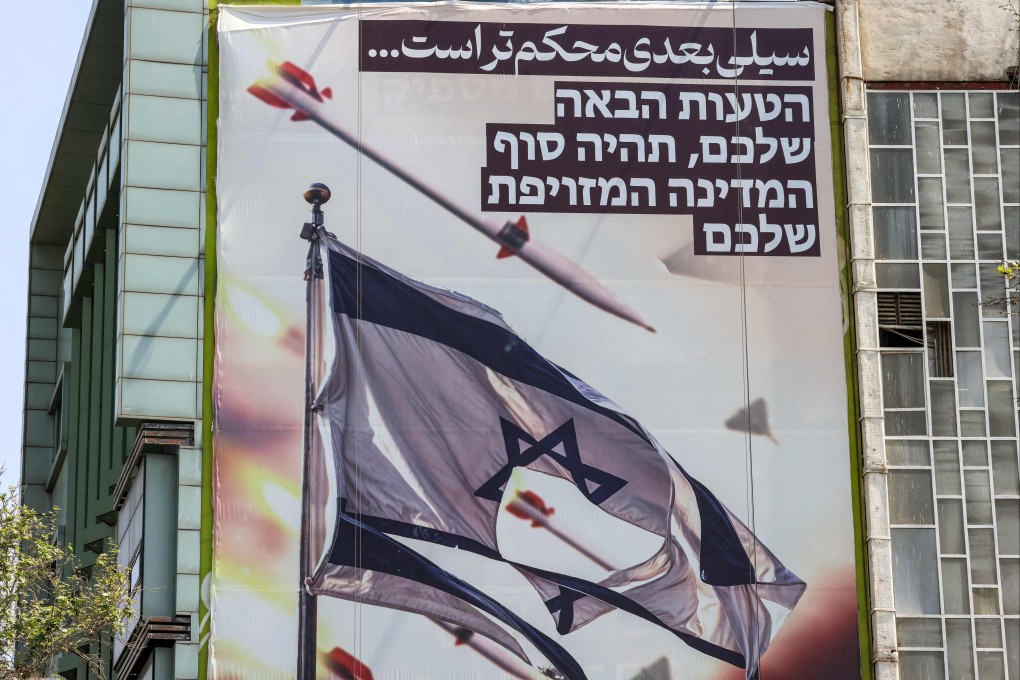 A banner depicting missiles and drones flying past a torn Israeli flag, with text in Persian reading “the next slap will be harder” and in Hebrew “your next mistake will be the end of your fake state”, on a building in Palestine Square in Tehran on April 14. Photo: AFP