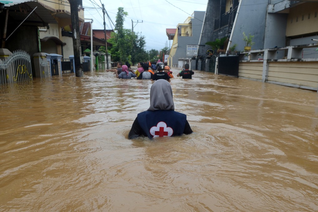 A volunteer wades through floods at a residential area in Makassar, South Sulawesi, Indonesia, on January 23, 2019. Photo: Antara Foto/Sahrul Manda Tikupadang/ via Reuters