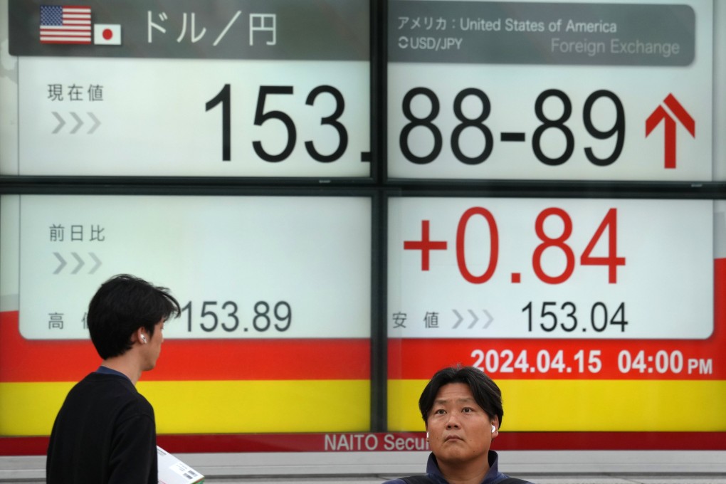 Pedestrians walk past a display showing the yen-US dollar exchange rate in Tokyo. The yen declined below the 153 level for the first time in 34 years on Monday. Photo: EPA-EFE
