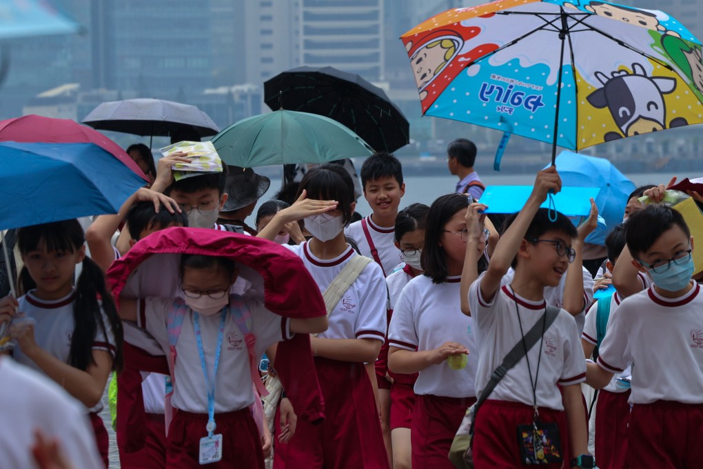 Children brave the wind and rain at Tsim Sha Tsui waterfront. The Observatory issued the first amber rainstorm warning of the year at 1pm on Thursday. Photo: Jelly Tse