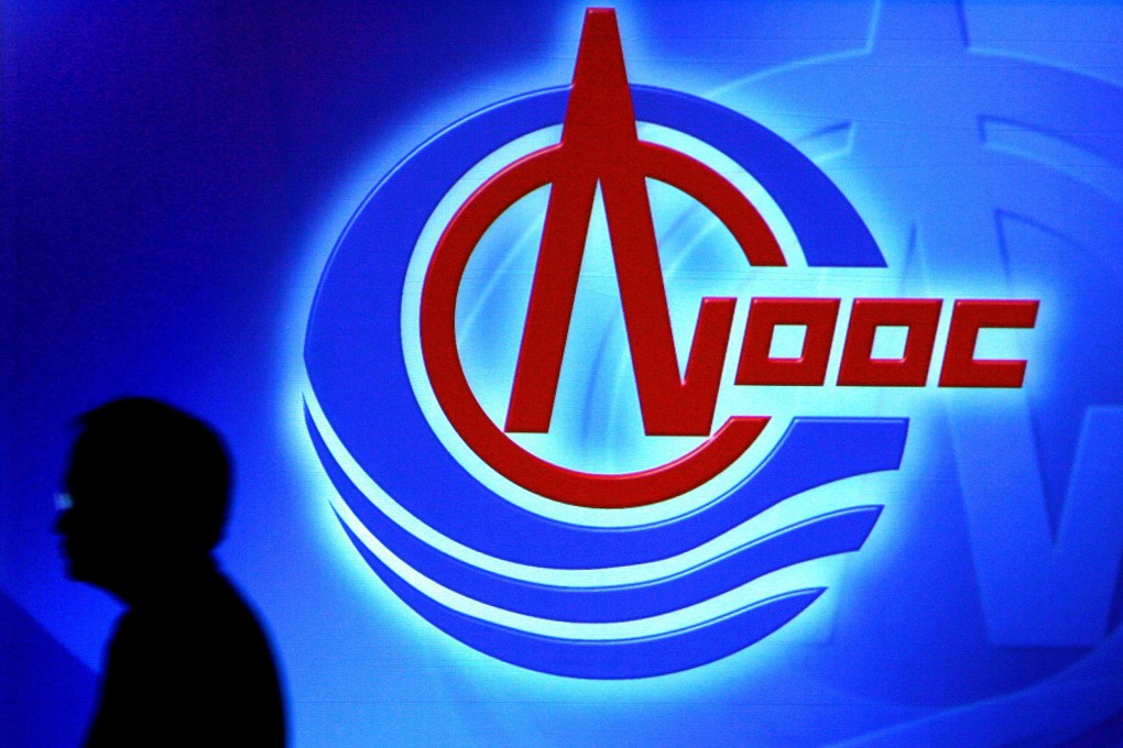A man walks by a screen showing the logo of China National Offshore Oil Corp (CNOOC) during a video press conference, in Hong Kong. Photo: AFP