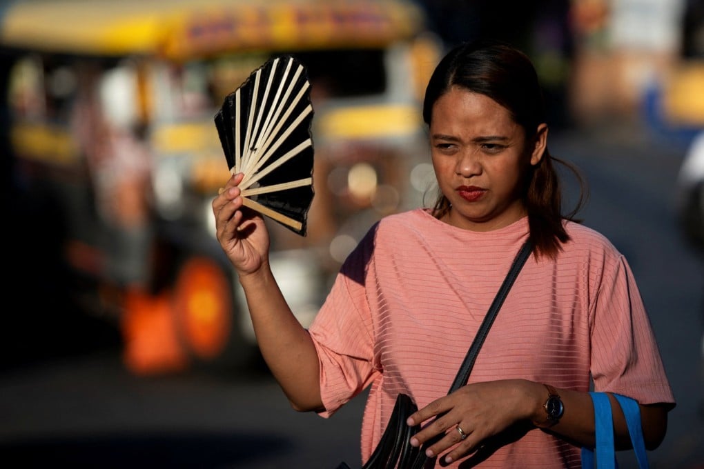 A woman uses a hand fan to cool herself during a hot day in Manila last week. Sweltering temperatures in the Philippine capital have forced many schools to switch to remote learning. Photo: Reuters