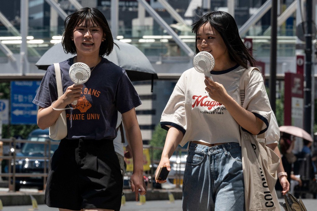Women use portable fans to cool off while walking around Tokyo last summer. Photo: AFP