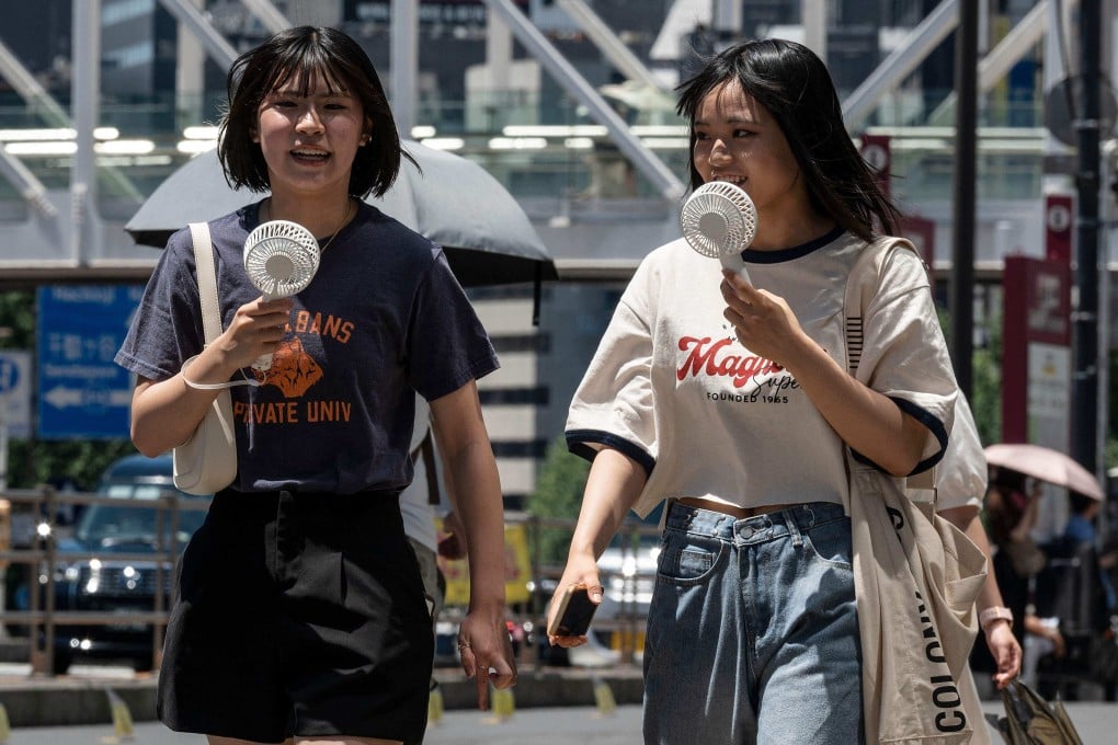 Women use portable fans to cool off while walking around Tokyo last summer. Photo: AFP