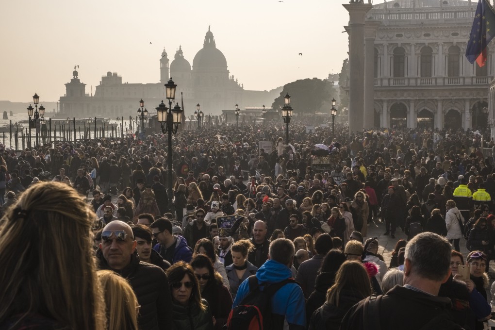 Thousands of people gathered along the Grand Canal in Venice to celebrate Carnival in 2019. The Italian city will begin requiring day trippers to buy tickets to enter its historic centre from Thursday, in the hope of reducing crowds at its popular sights. Photo: Getty Images
