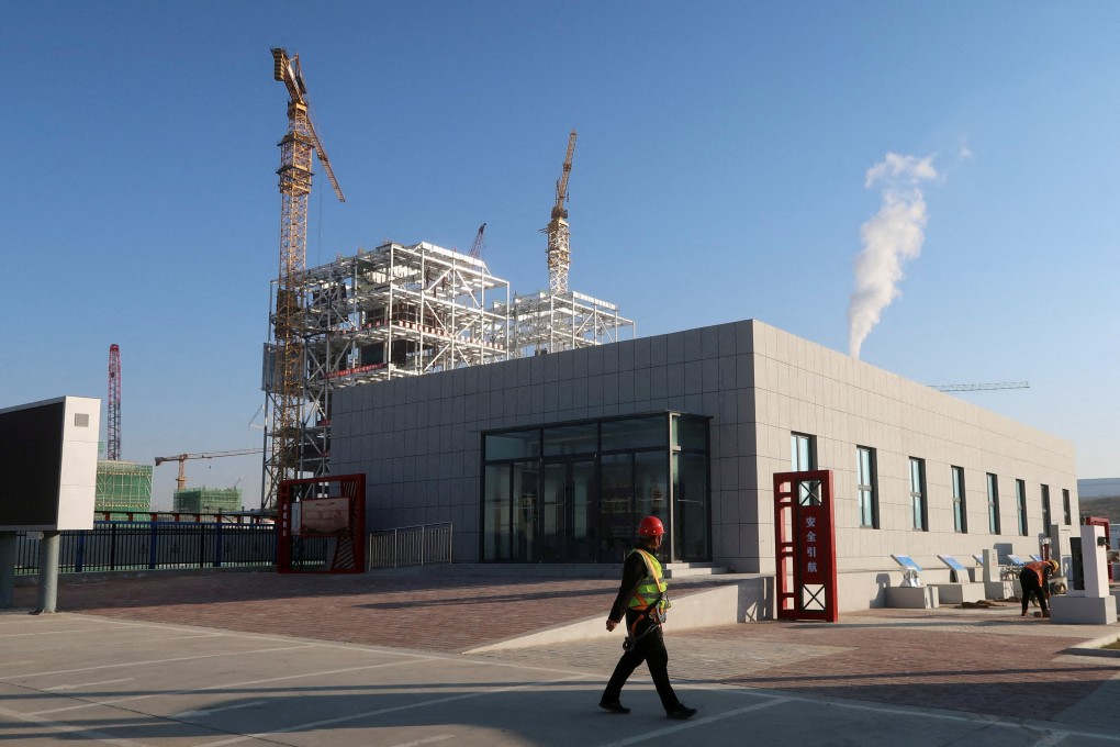 A worker walks past cranes at a coal-fired power plant under construction in Yulin, Shaanxi province in 2023. Photo: Reuters