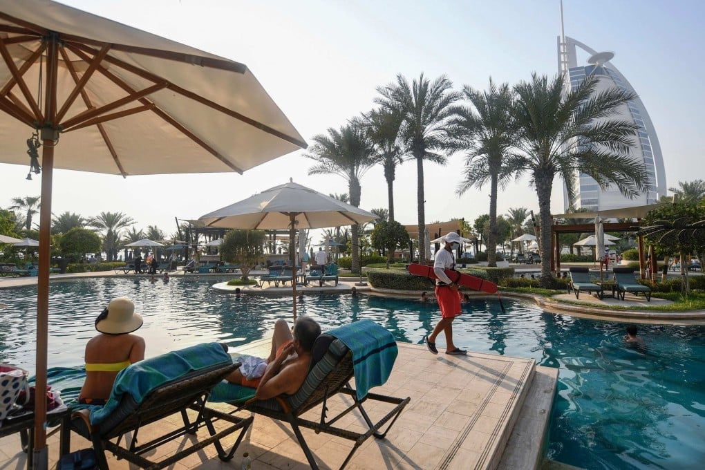 Tourists sunbathe by the pool of the Al Naseem hotel in the Gulf emirate of Dubai in the United Arab Emirates, on July 7, 2020, with a view of the Burj al-Arab hotel in the background. Photo: AFP