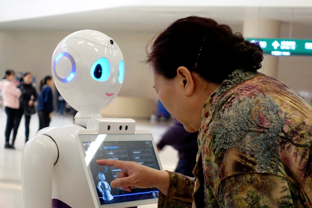 A woman touches a screen on a robot at the outpatient hall of People’s Liberation Army General Hospital in Beijing, China, on March 16, 2017. Photo: Reuters
