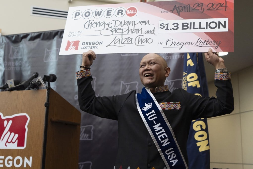 Cheng “Charlie” Saephan displays a cheque above his head after it was revealed that he was one of the winners of the $1.3 billion Powerball jackpot on Monday. Photo: AP