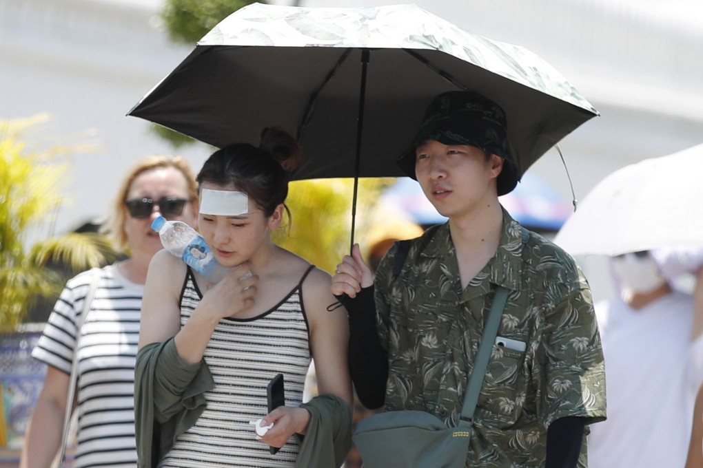 Chinese tourists use a parasol to shield themselves from the sun as they visit the Grand Palace in Bangkok on Monday. Deaths related to heat have risen to about 30 in Thailand this year. Photo: EPA-EFE