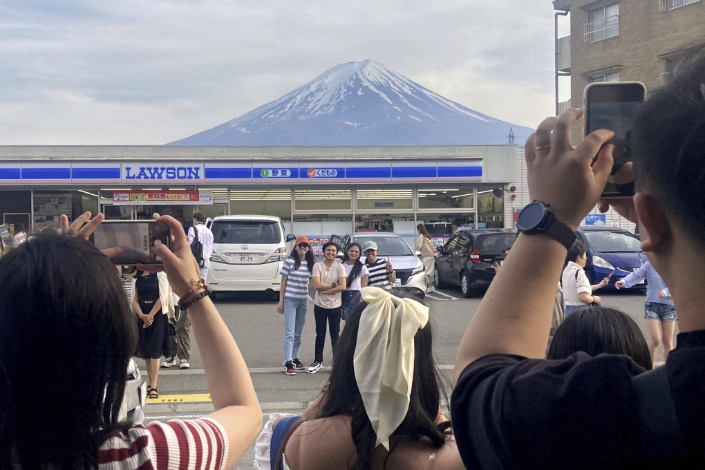 Visitors take a photo of Mount Fuji in front of a convenience store at Fujikawaguchiko town on Sunday. Photo: Kyodo News via AP
