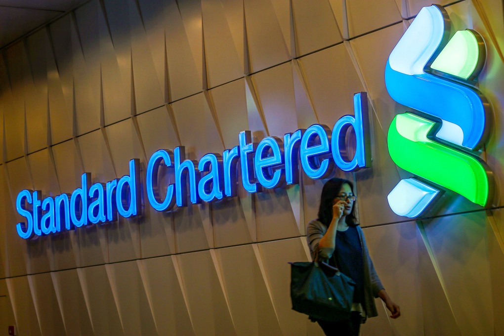 A woman passes a Standard Chartered Bank logo in Central. Photo: K. Y. Cheng