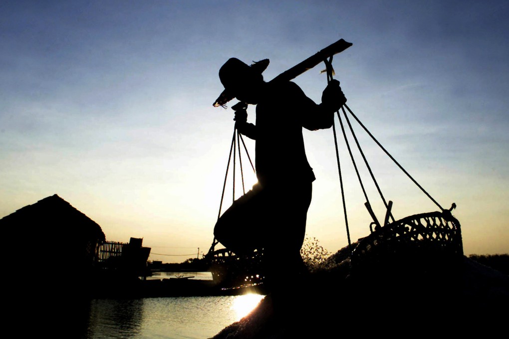 An Indonesian salt farmer carries baskets of salt. Most salt is industrially processed but in Bali, it is won from the sea by farmers who harvest it by hand. Photo: Reuters