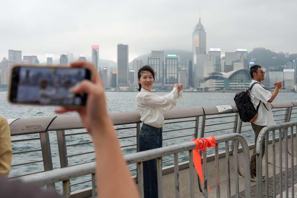 A mainland tourists strikes a pose imitating Hong Kong tycoon Li Ka-shing at the Tsim Sha Tsui waterfront on the second day of the ‘golden week’ holidays despite rain and wind. Photo: Eugene Lee