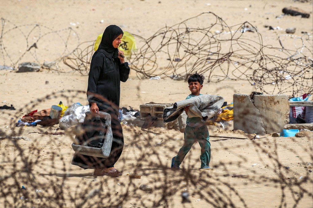 A woman and boy walk with belongings past barbed-wire fences as they flee from Rafah in the southern Gaza Strip on Saturday. Photo: AFP