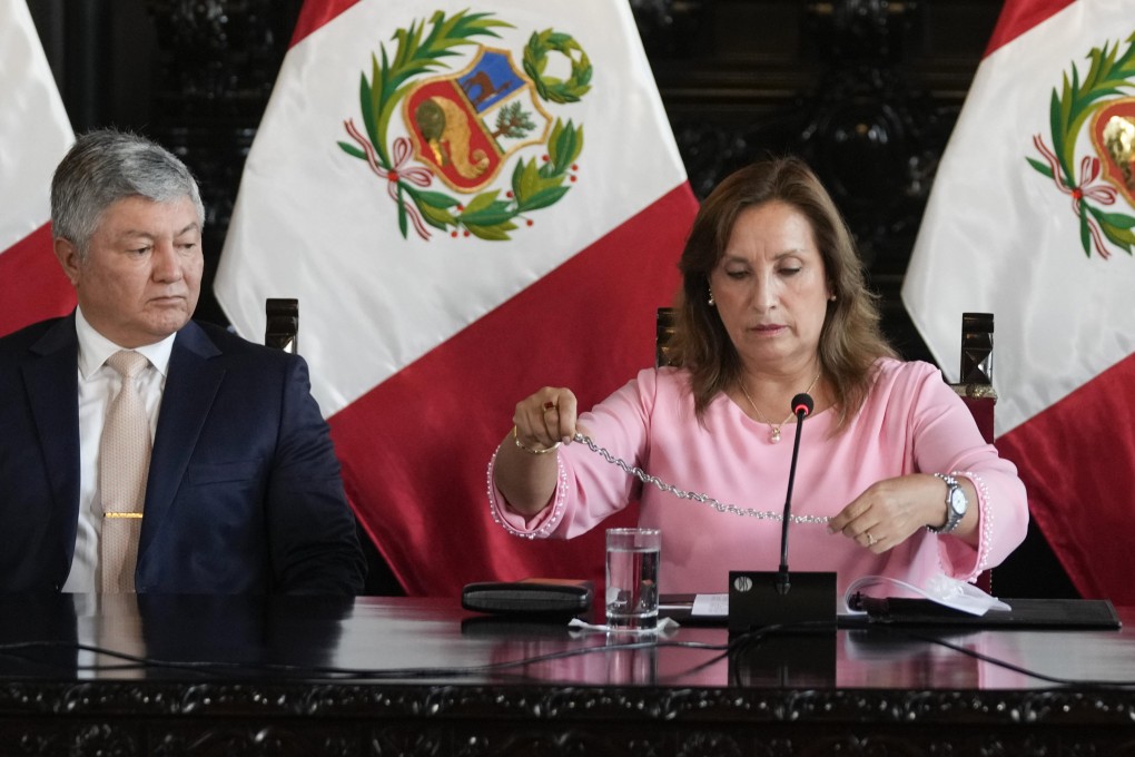 Peruvian President Dina Boluarte, accompanied by her lawyer Mateo Castaneda, shows her necklace to the media at the government palace in Lima in April amid an investigation into whether she illegally received cash, luxury watches and jewellery. Photo: AP