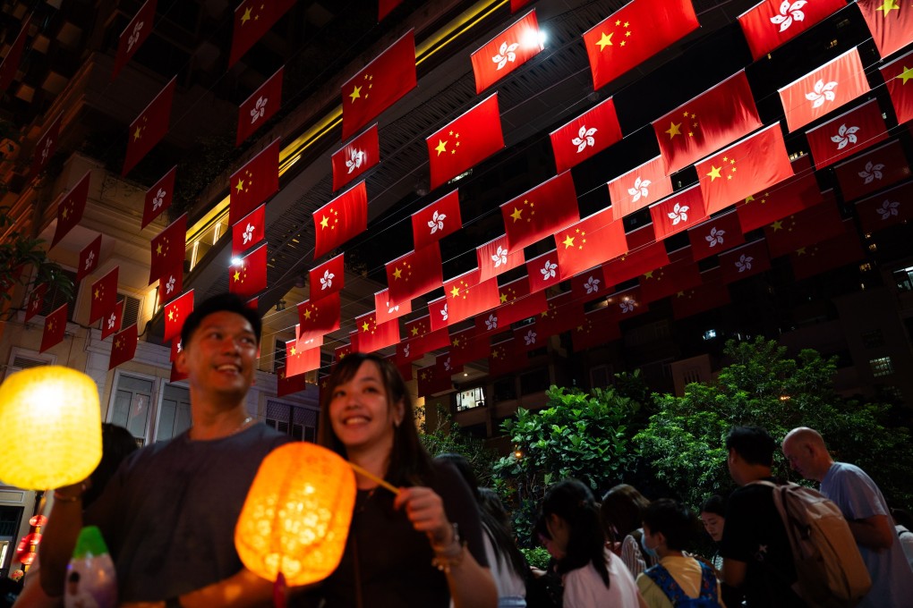 People walk past the Chinese national and Hong Kong flags on October 1, 2023. PhotoL EPA-EFE