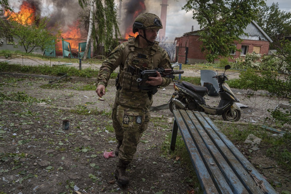 A police officer near a burning house destroyed by a Russian air strike in Vovchansk, Ukraine. Photo: AP