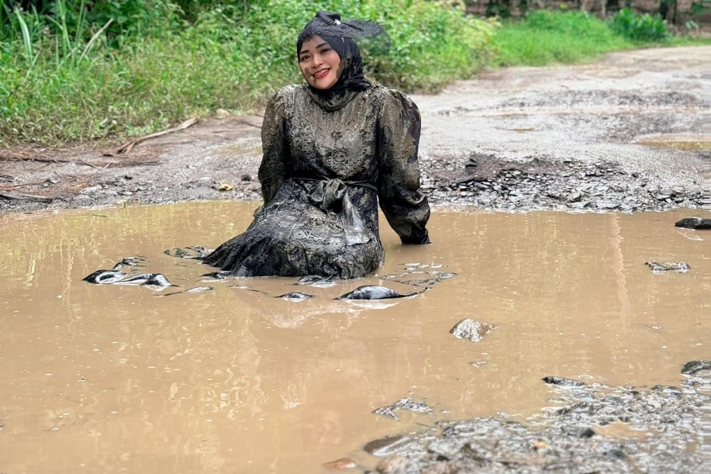 Ummu Hani sitting in mud-filled potholes on a road in Merbau Mataram, Indonesia’s southern Sumatra province. Photo: Facebook/ummuhanii