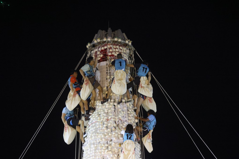 Competitors scramble up a bamboo tower lined with plastic buns during the annual contest on Cheung Chau island on Thursday morning. Photo: Yik Yeung-man