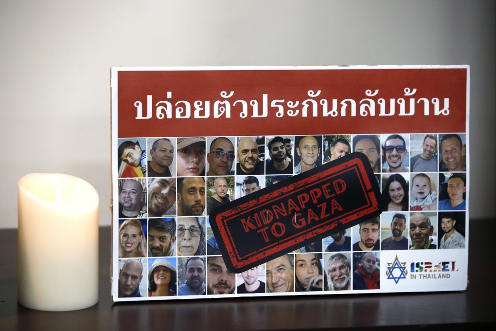 A candle is lit next to photographs of hostages at the Israeli embassy in Bangkok, Thailand, on Monday. Photo: EPA-EFE