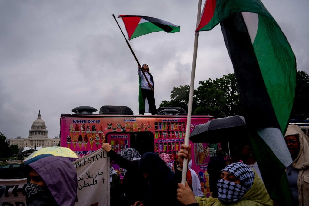The Dome of the US Capitol Building is visible as Layan Barmil of Virginia stands on a food truck and waves a Palestinian flag. Photo: AFP