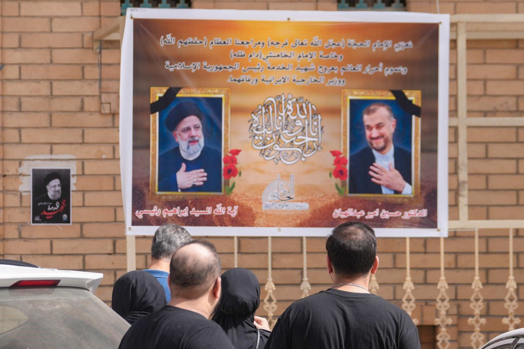 People walk in the central Iraqi holy city of Najaf, past portraits of Iran’s President Ebrahim Raisi (left) and Foreign Minister Hossein Amir-Abdollahian (right) who died in a helicopter crash on Monday. Photo: AFP