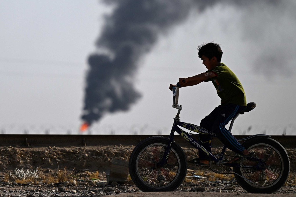 An Iraqi youth rides his bicycle near a flare stack in the Rumaila oilfield near Iraq’s southern port city of Basra on May 5. Chinese firms oversee two-thirds of Iraq’s oil production. Photo: AFP