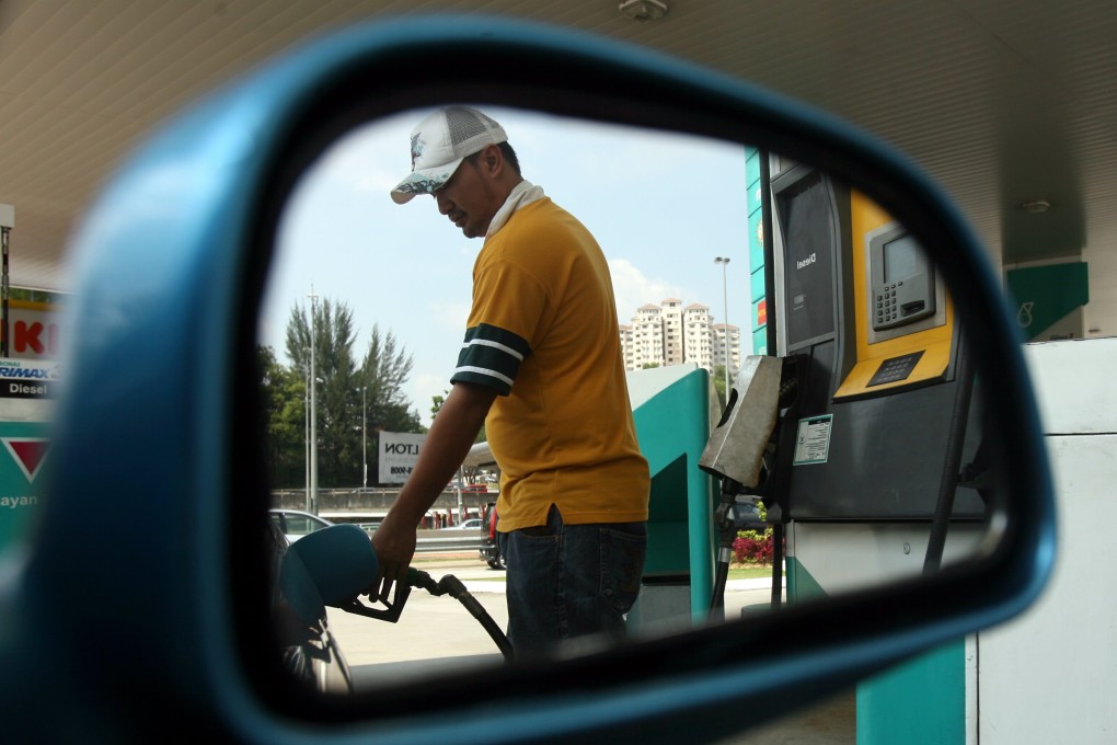 A man fills the tank of a car at a petrol station in Kuala Lumpur. Photo: AFP