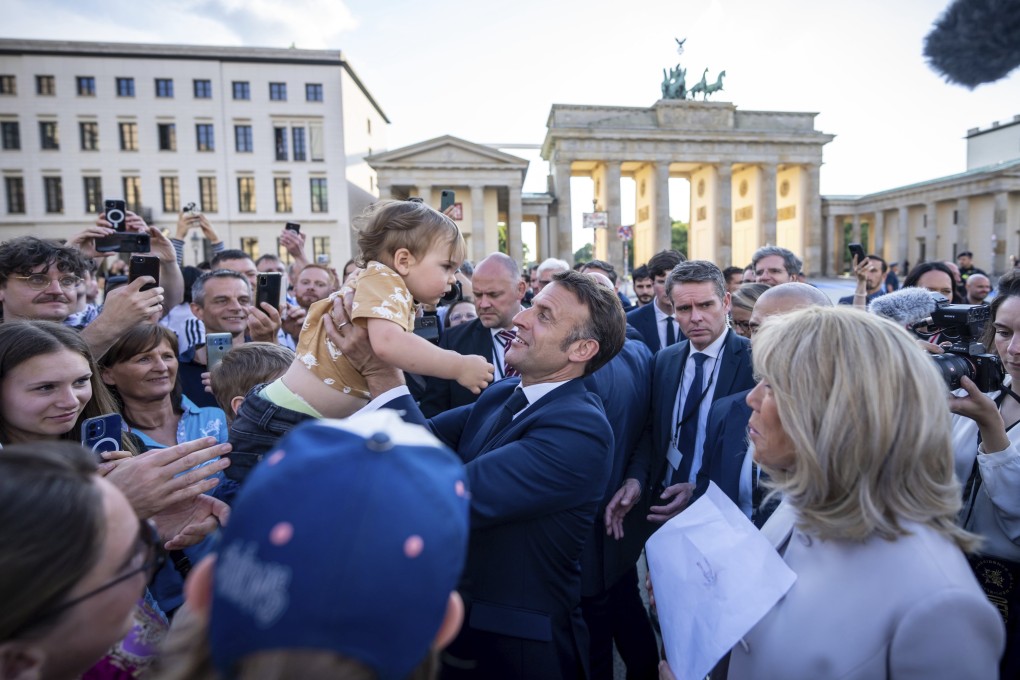 France’s President Emmanuel Macron holds a baby in Berlin, Germany on Sunday. Photo: dpa via AP