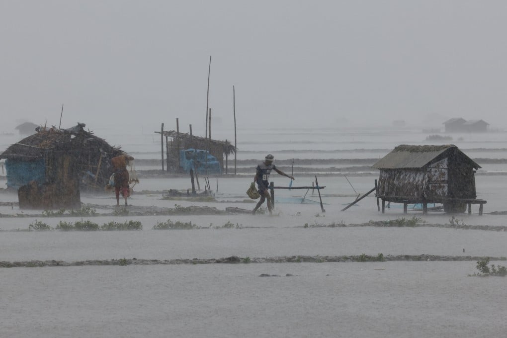People walk through heavy rain on Monday at shrimp and crab farms in the Shyamnagar area of Satkhira, Bangladesh, as Cyclone Remal passes the country. Photo: Reuters