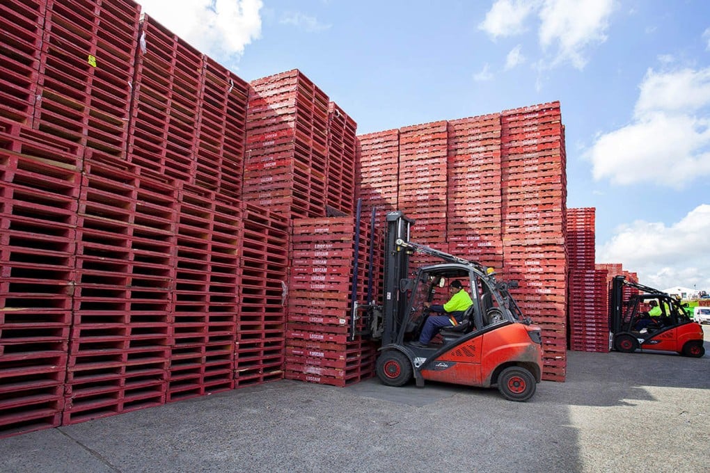 A worker stacks Loscam pallets at a facility in Australia in this undated photo. Photo: Loscam