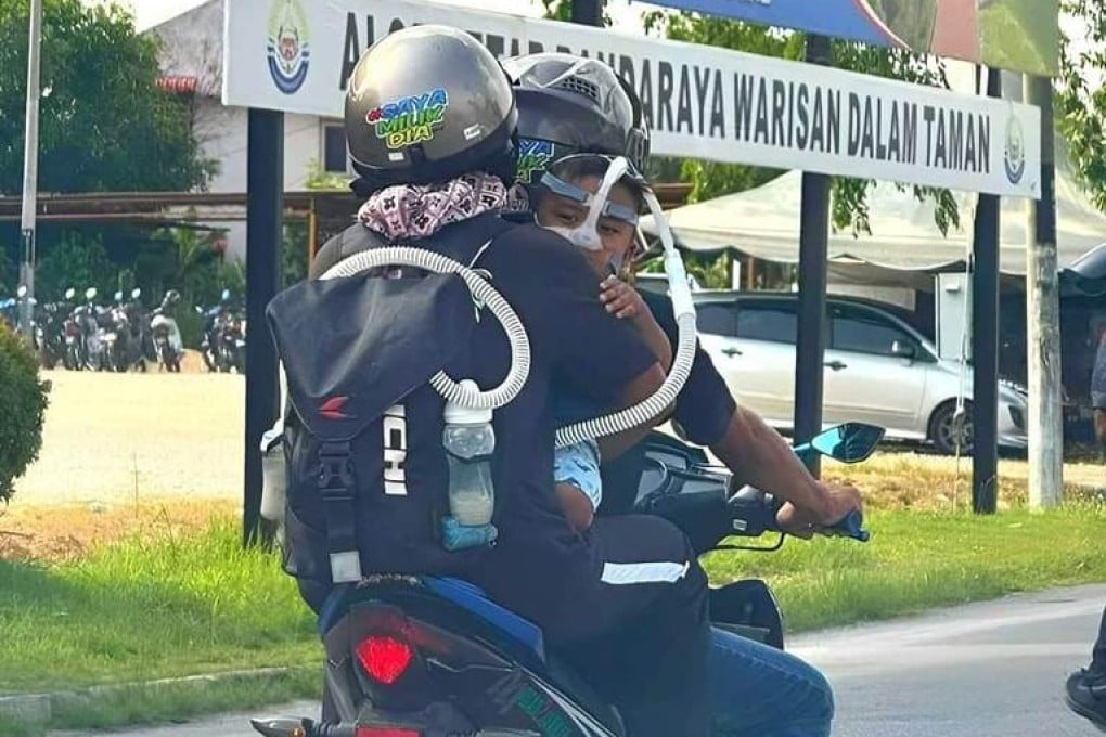 Norhidayu Halim holding her baby who is dependent on a breathing device on a motorcycle with Azlan Ishak. Photo: Facebook/ganu.pie